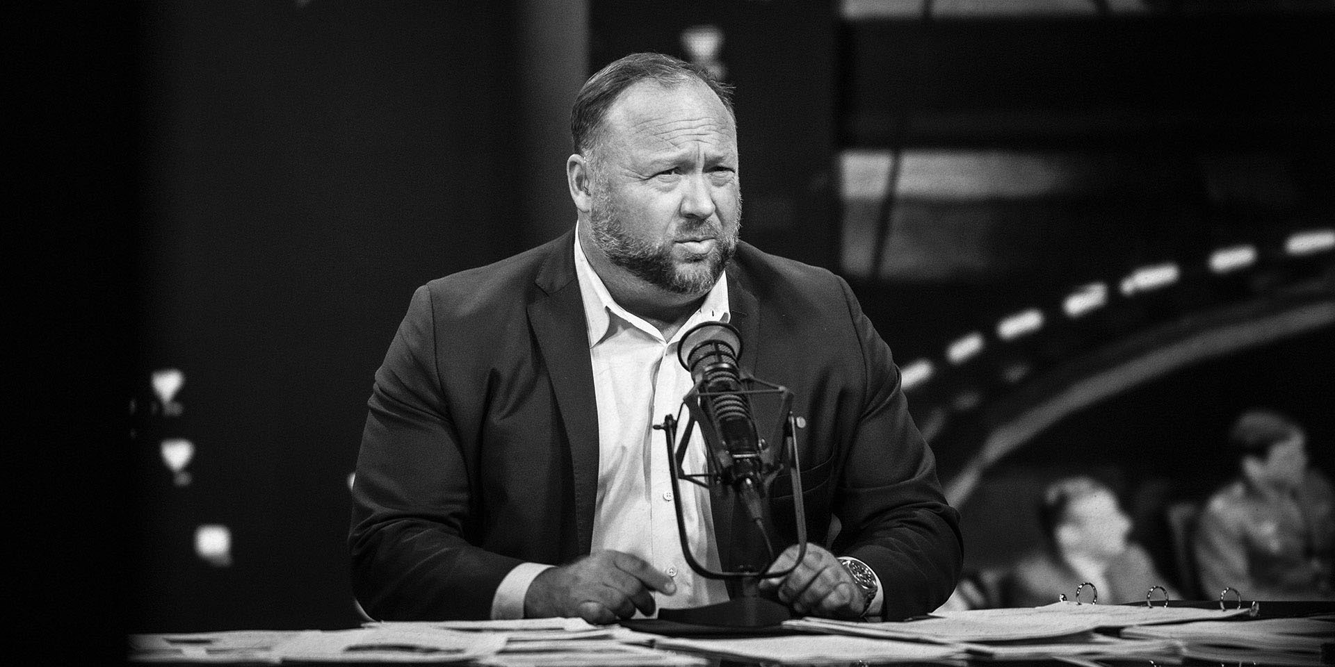 Person seated in front of microphone on desk.