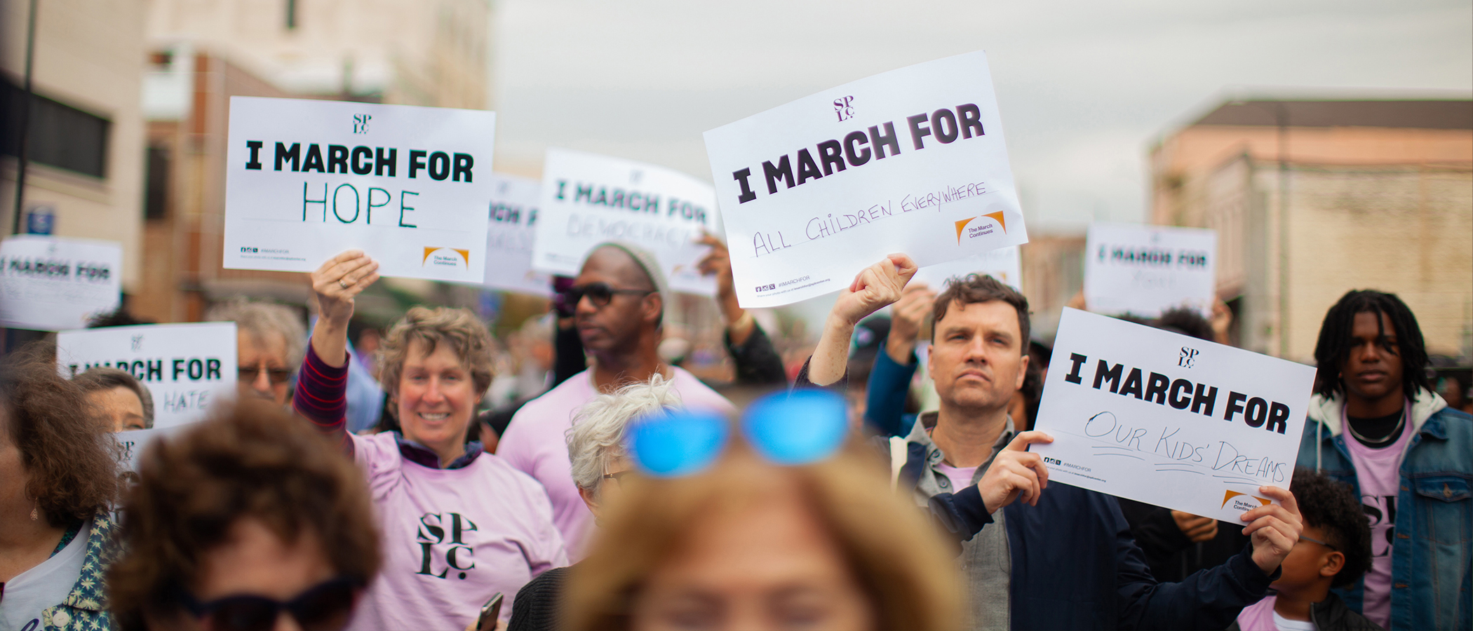 People hold signs as they march.