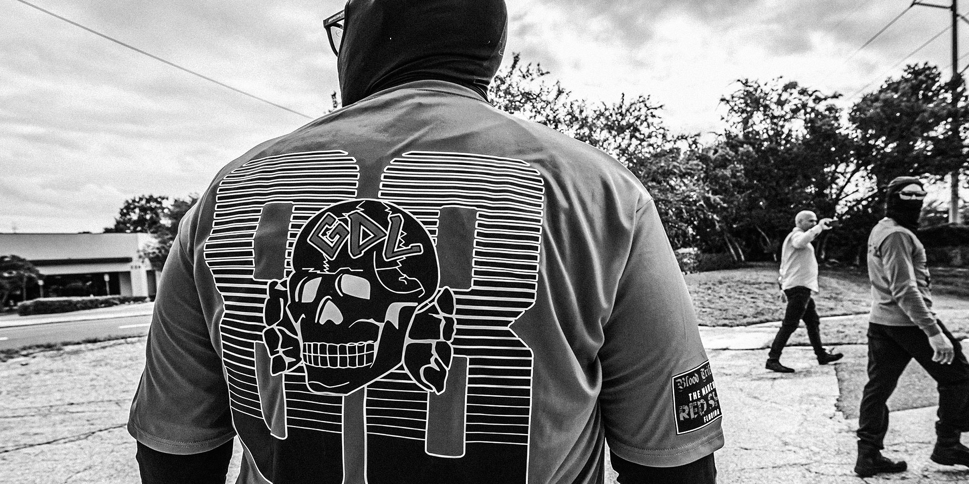 Black and white image of back of person wearing Goyim Defense League paraphernalia.