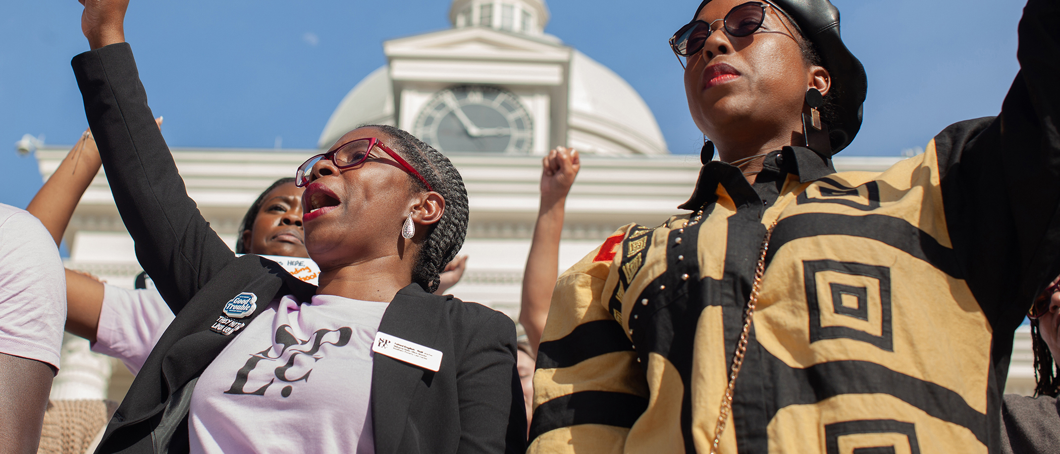 People with raised clinched fists outside a state capitol building.