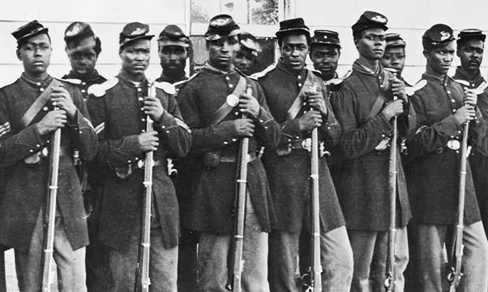 Black Union soldiers standing outside in a line in uniform looking at the camera