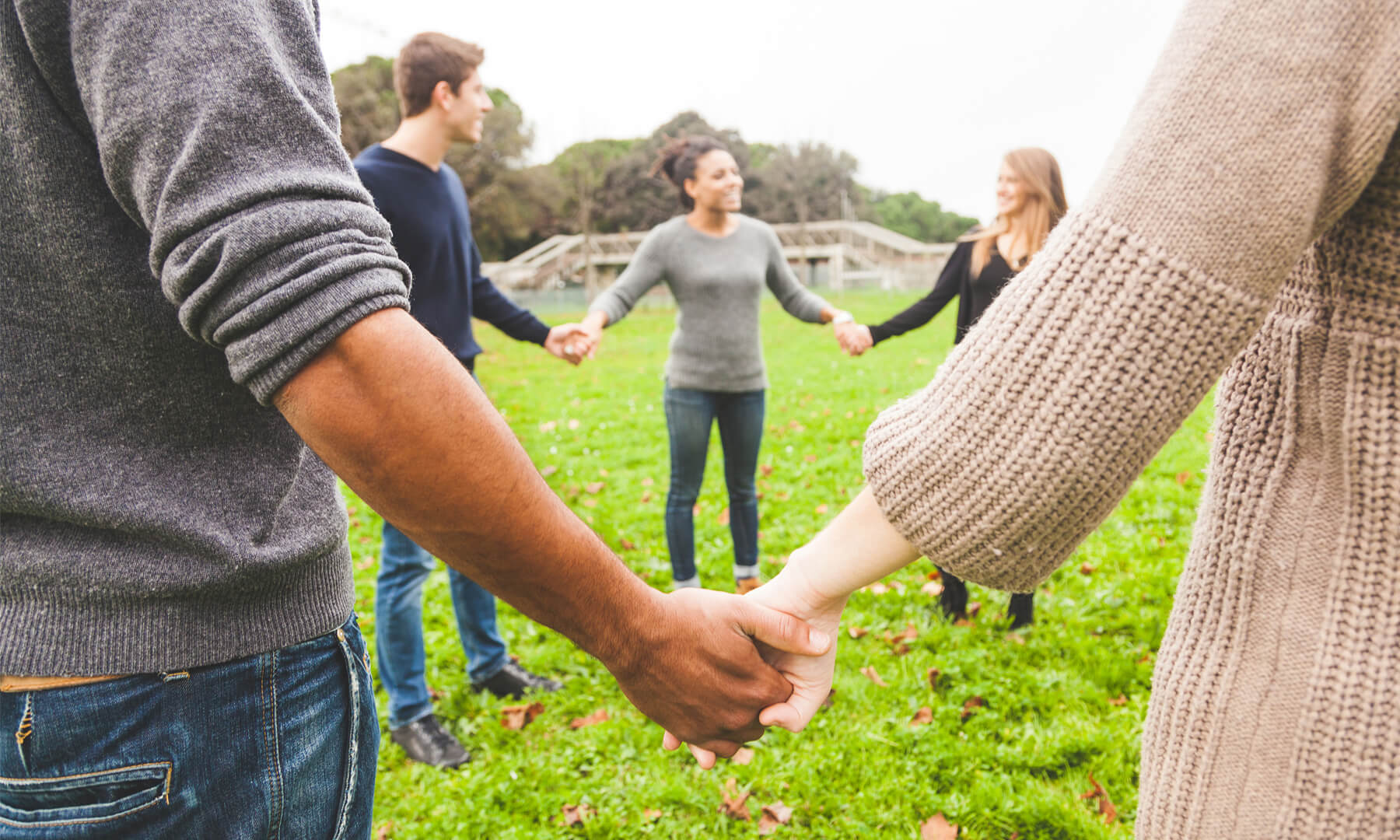 Young people stand in a circle holding hands