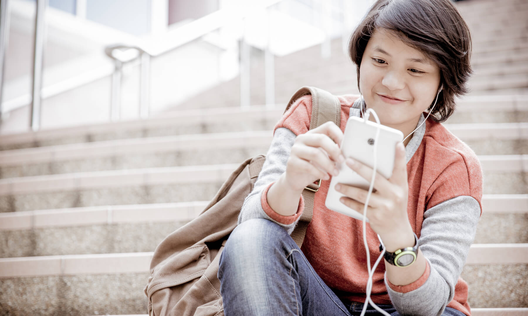 student on steps looking at cell phone smiling