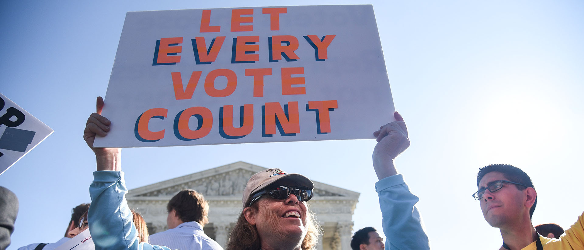Person holding sign that reads “Let Every Vote Count” outside the U.S. Supreme Court building.