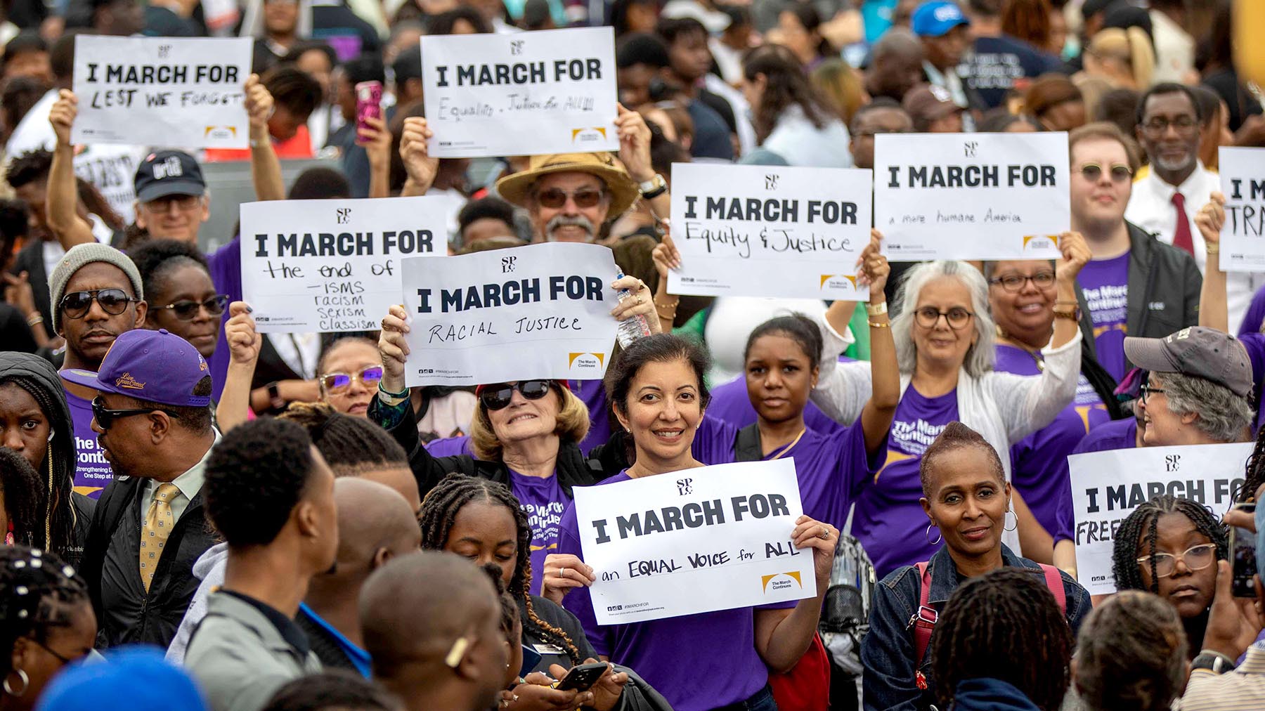 People outside hold signs "I March for" to honor others during the 59th anniversary of Bloody Sunday.